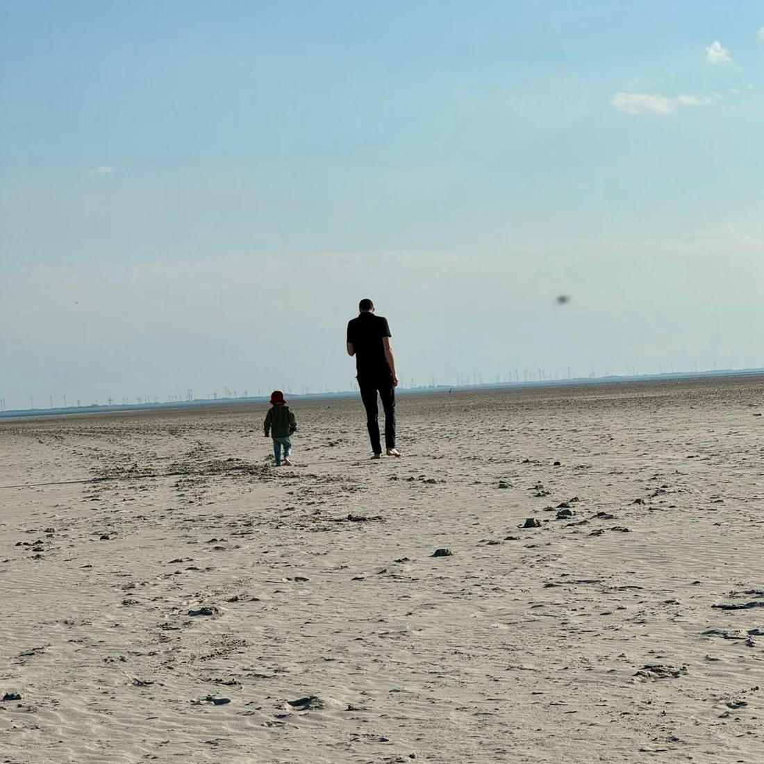 Andreas Etzkorn mit seiner Tochter von hinten am Strand von Spiekeroog